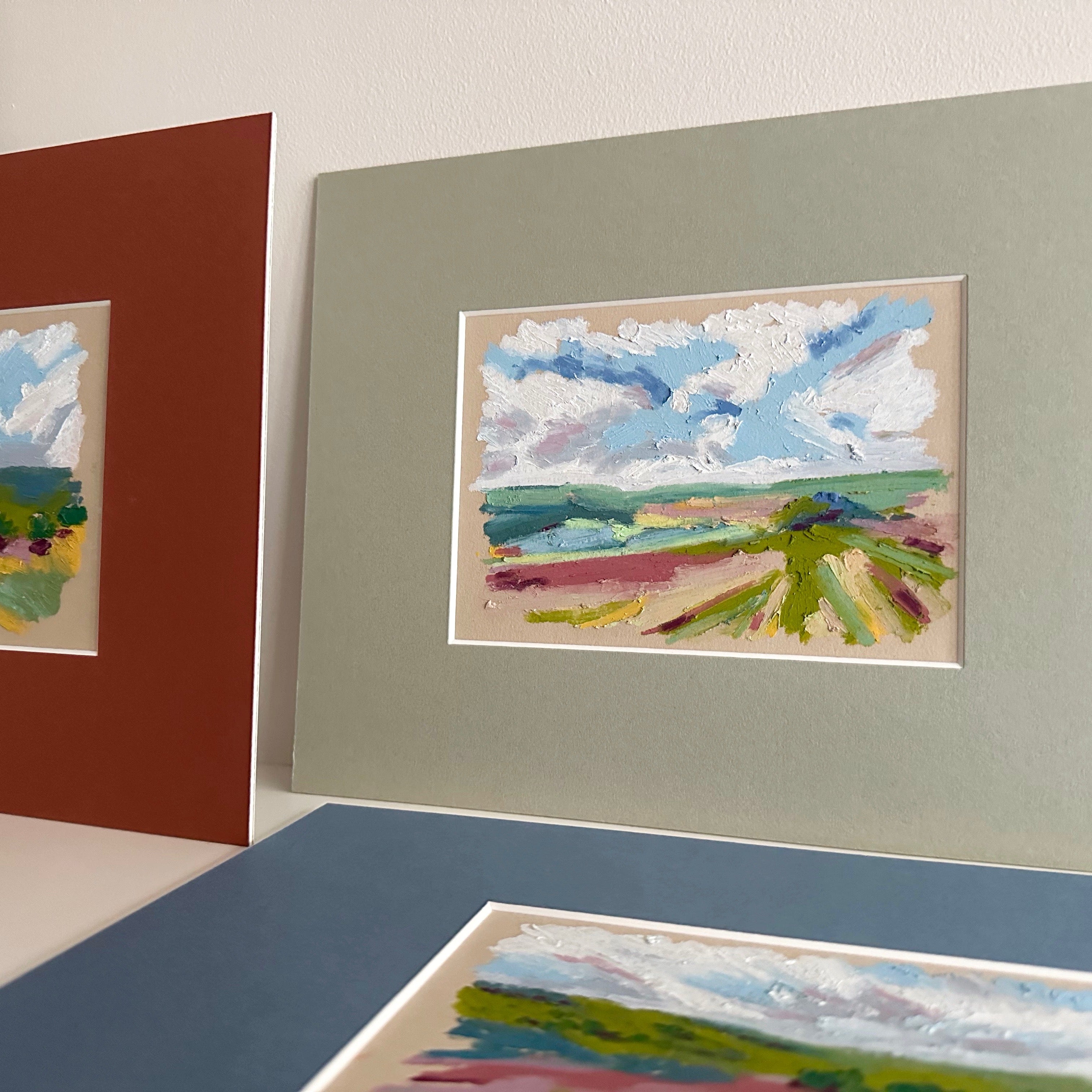 Three framed artworks of landscapes on a neutral background