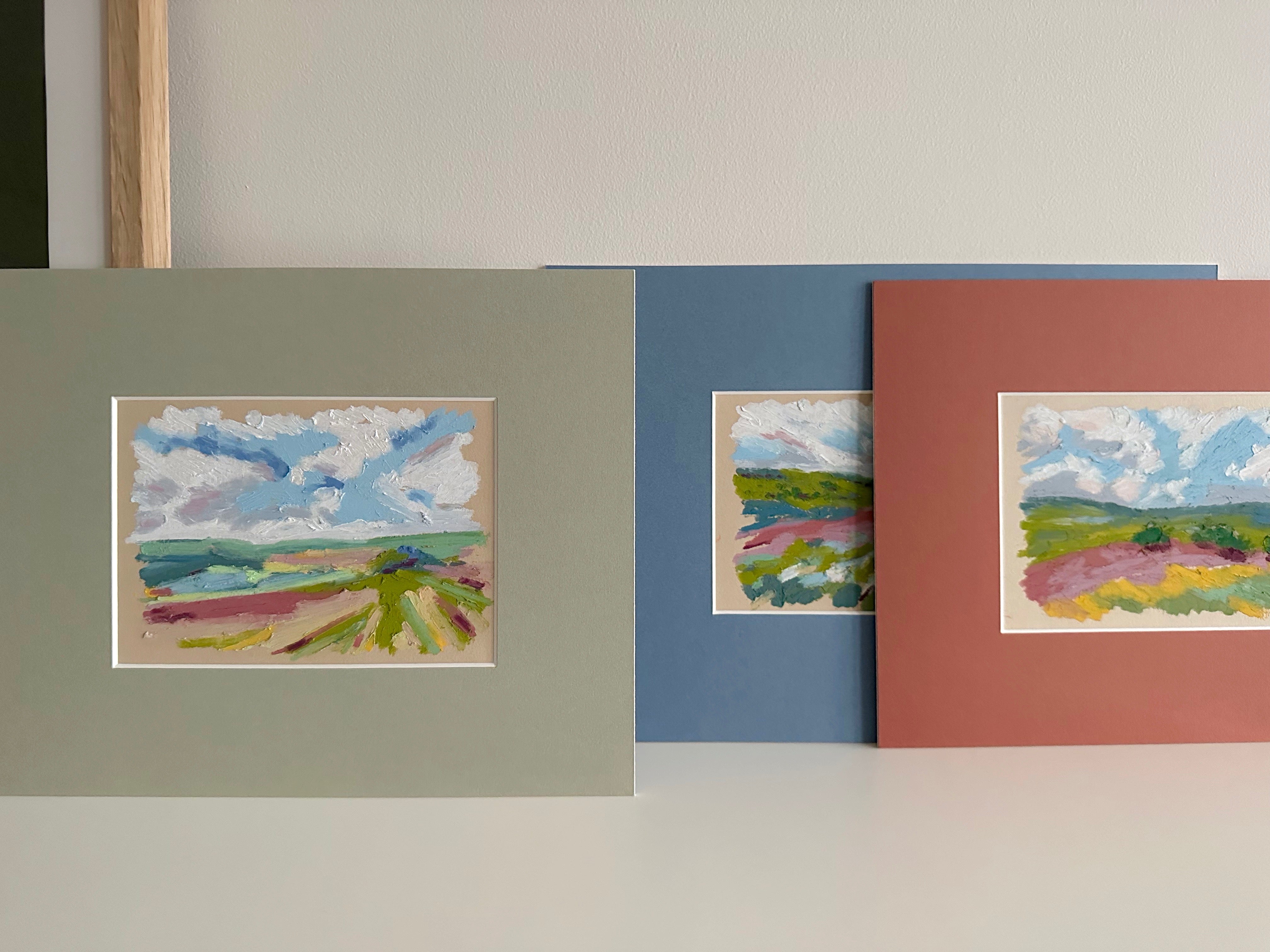 Three framed artworks of landscapes on a plain wall.